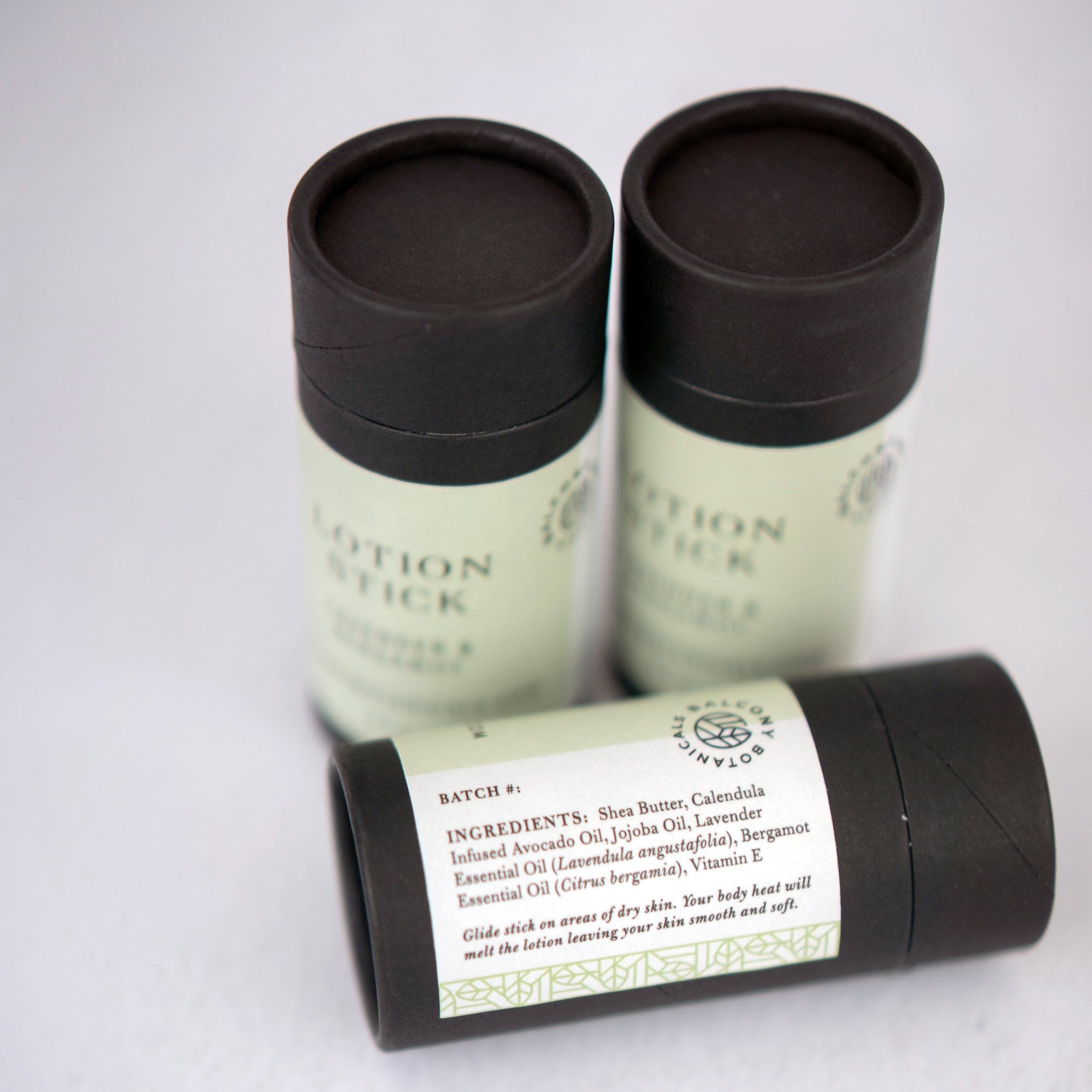 Lavender & Bergamot Lotion Stick in black cardboard push up tube showing label with ingredients. 