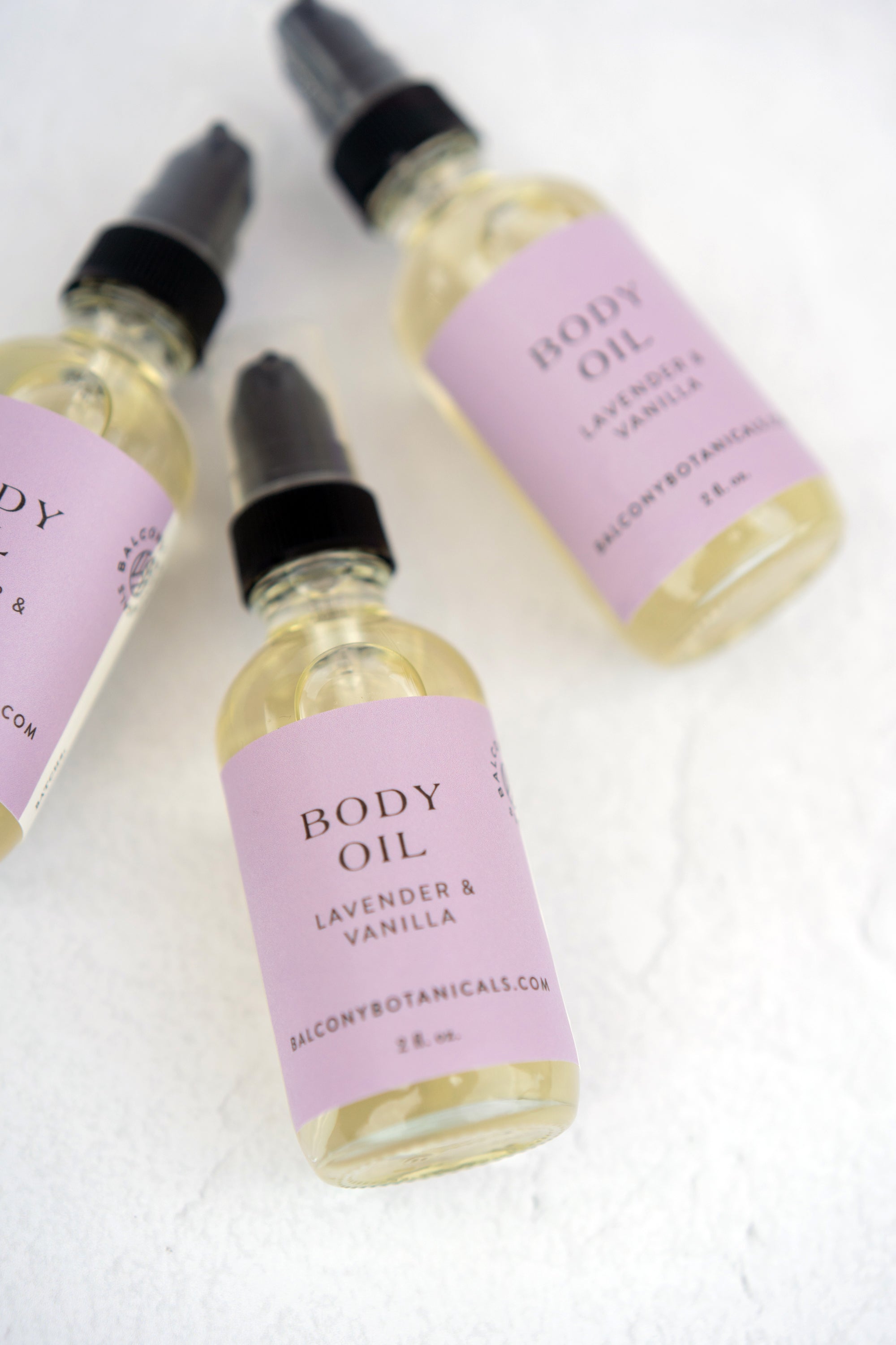 3 bottles Lavender & Vanilla Body Oil on a flat surface