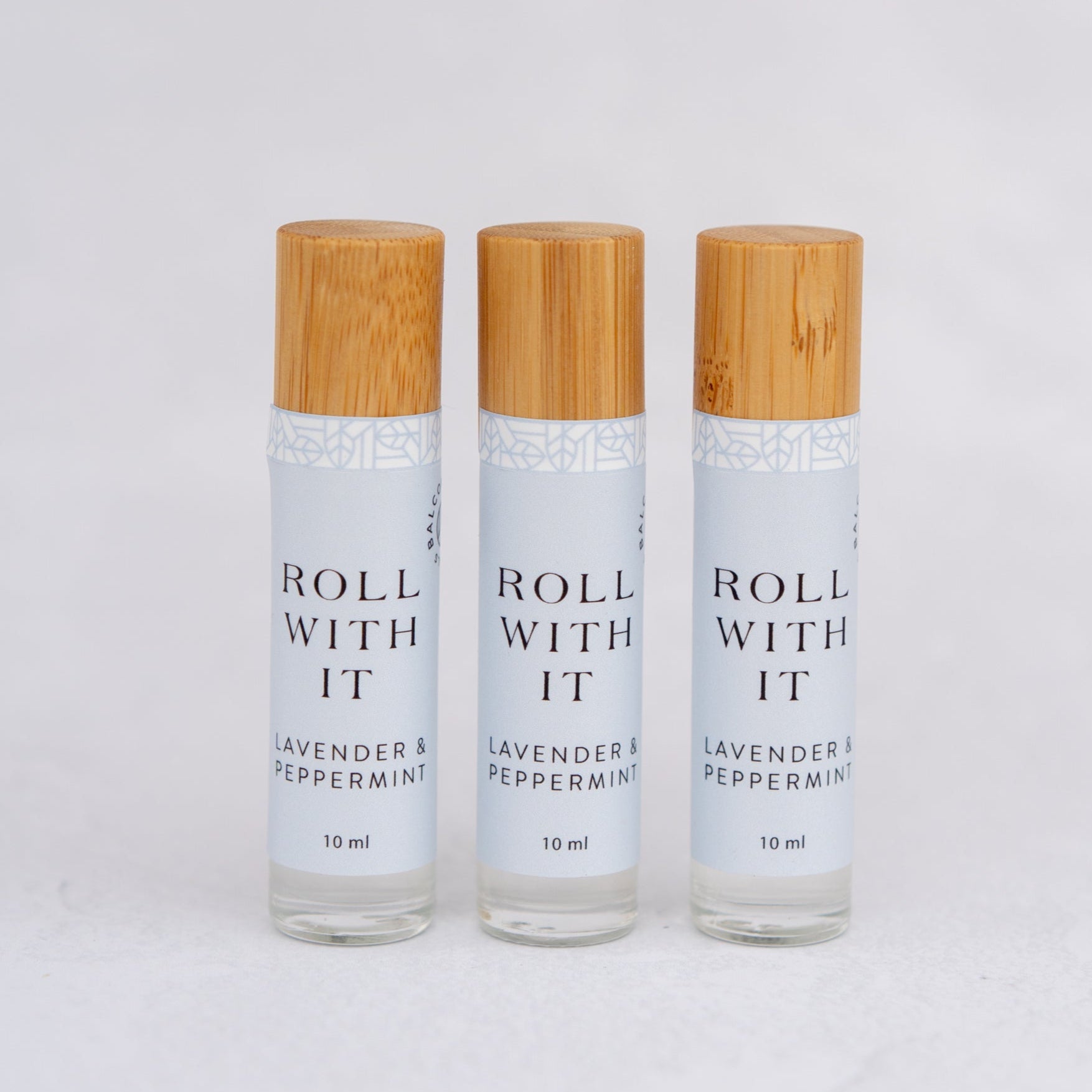 Three Lavender & Peppermint Aromatherapy roller ball bottles with bamboo caps. 