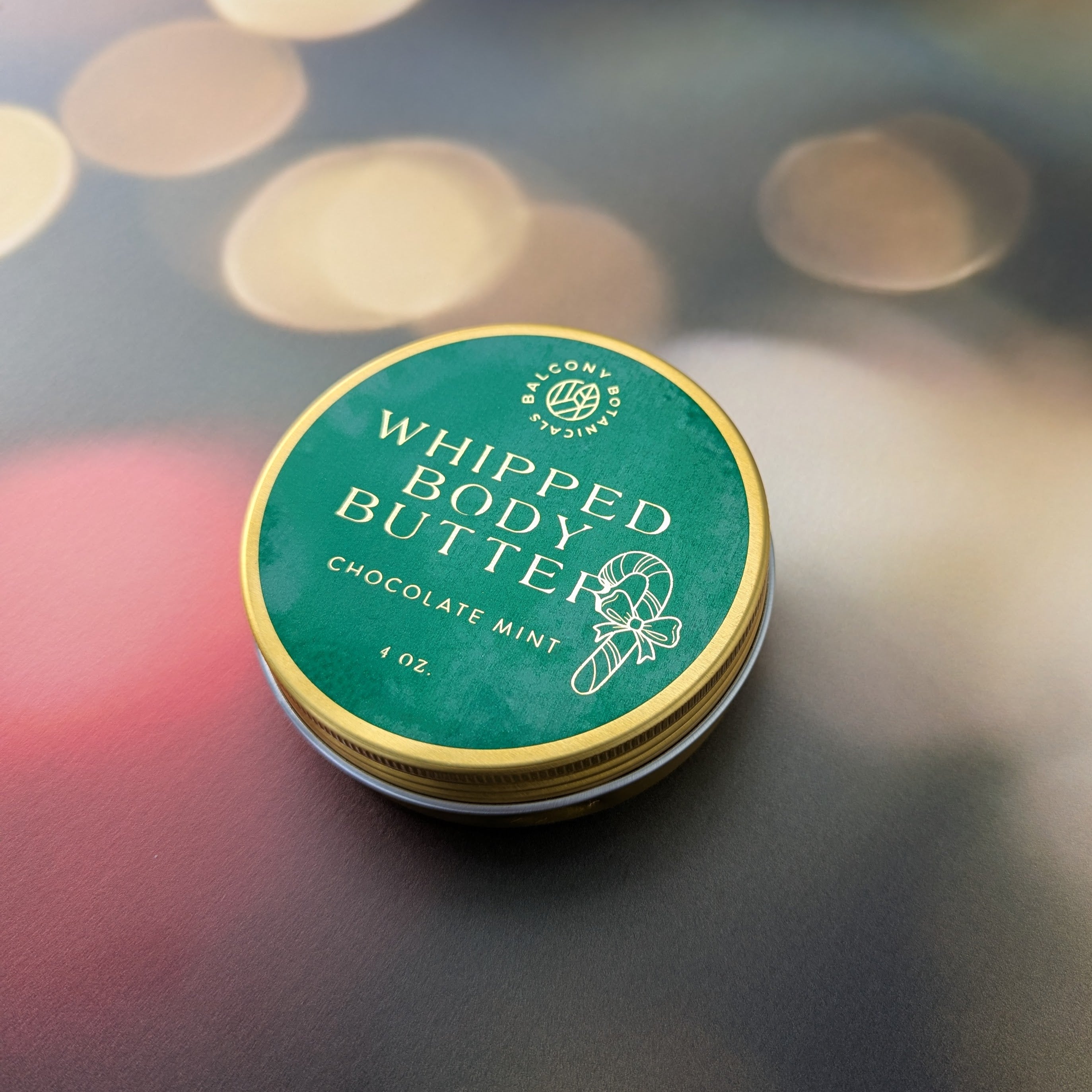 chocolate mint body butter in a gold tin with a green and gold label